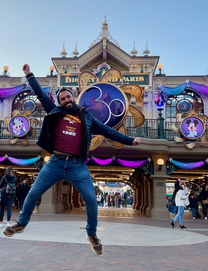 Chico saltando frente a la entrada a Disneyland Paris decorada del 20 aniversario